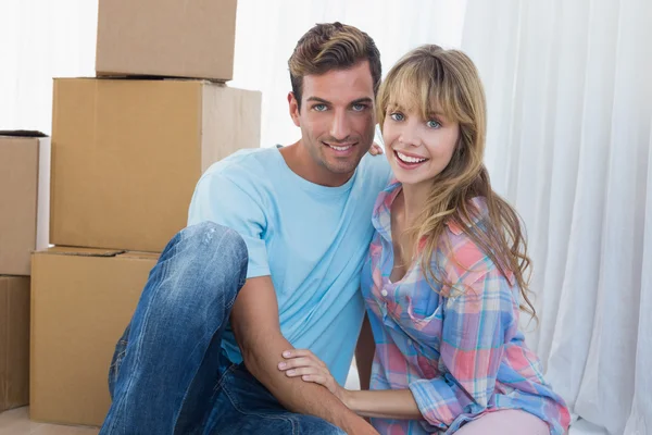 Couple sitting against cardboard boxes in new house — Stock Photo, Image