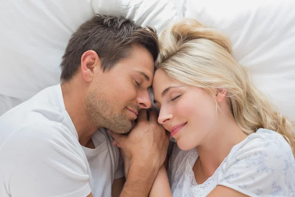Verliefde paar liggend in bed met de ogen gesloten — Stockfoto