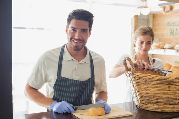 Smiling waiter with croissant at the coffee shop counter — Stock Photo, Image