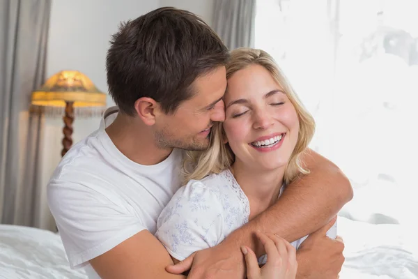 Loving man embracing woman from behind at home — Stock Photo, Image