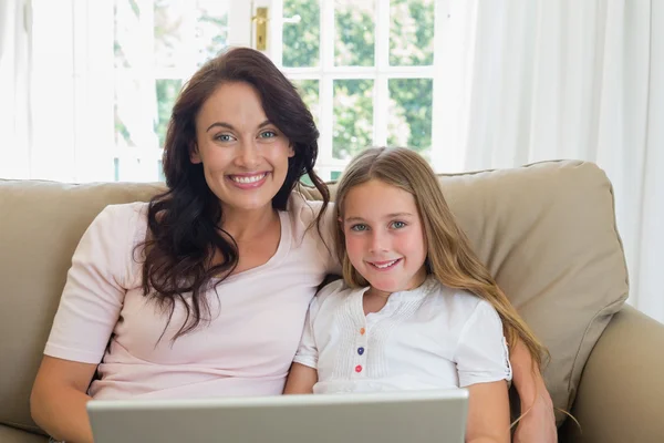 Moeder en dochter met laptop op sofa — Stockfoto