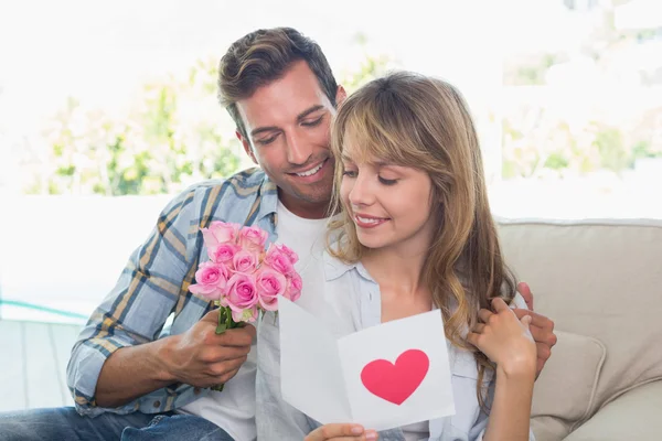 Casal amoroso com flores e cartão de saudação — Fotografia de Stock