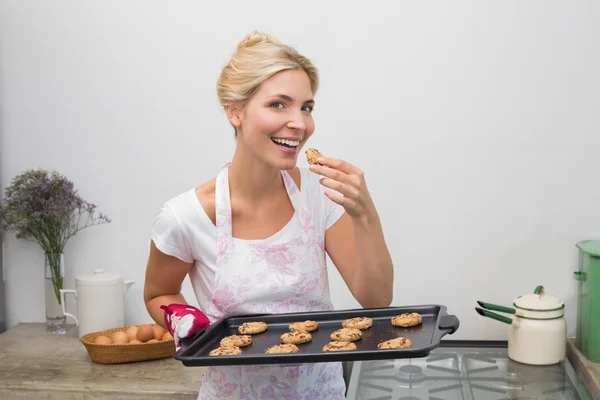 Jonge vrouw met een lade van cookies in keuken glimlachen — Stockfoto