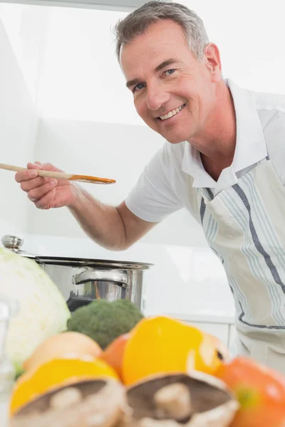 Man preparing food with vegetables in the foreground — Stock Photo, Image