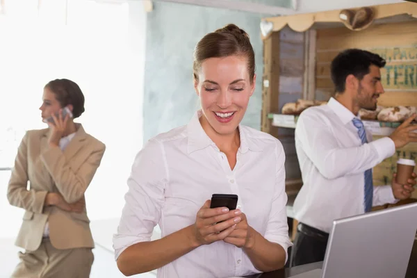 Empresária usando telefone celular e laptop no refeitório do escritório — Fotografia de Stock