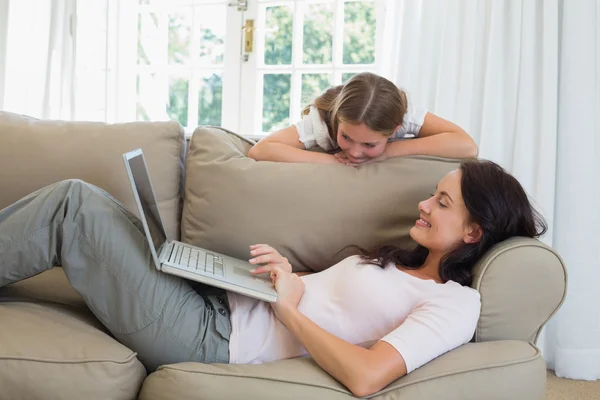 Mère utilisant un ordinateur portable tandis que sa fille le regarde — Photo