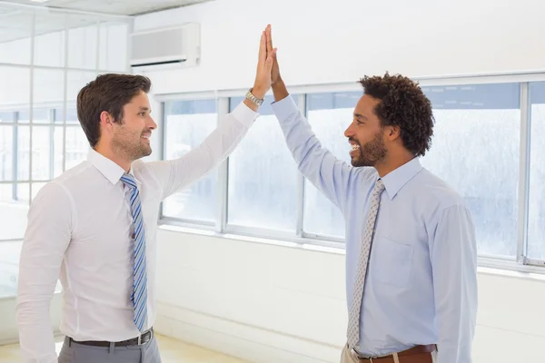Smiling businessmen joining hands together in office — Stock Photo, Image