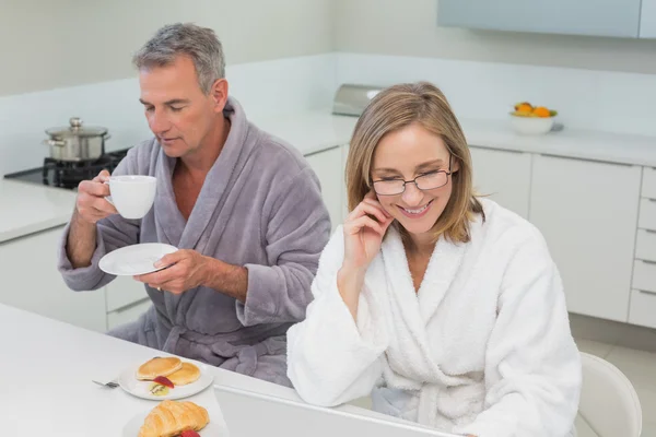 Couple in bathrobes having breakfast in kitchen — Stock Photo, Image