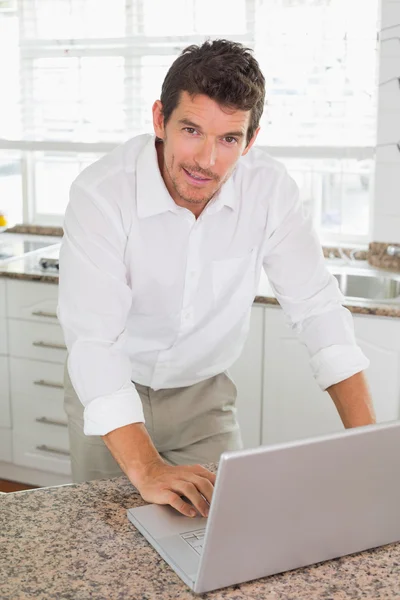 Jovem sorridente usando laptop em casa — Fotografia de Stock