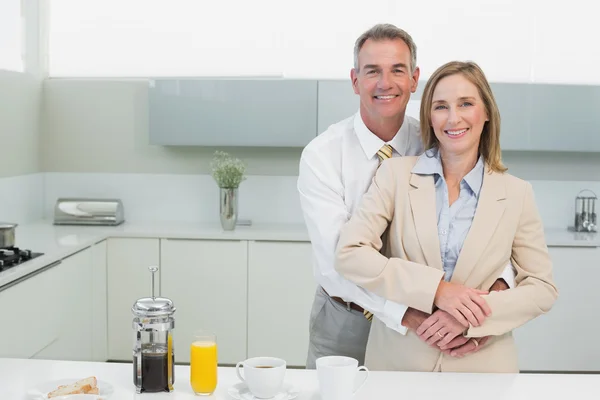 Businessman embracing woman from behind in kitchen — Stock Photo, Image