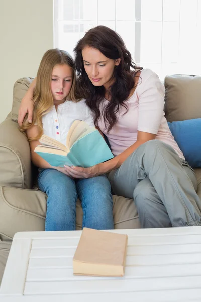 Meisje en moeder lezing roman op sofa — Stockfoto