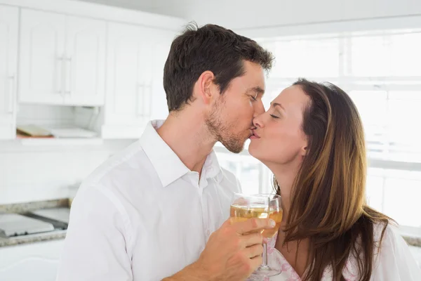 Amante pareja besándose con copa de vino en la mano en la cocina — Foto de Stock