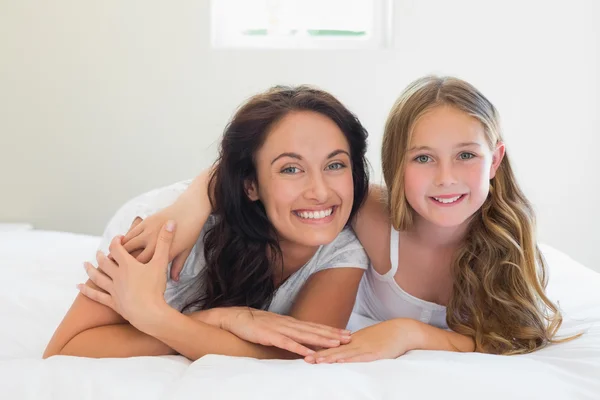 Sonrientes madre e hija acostadas en la cama —  Fotos de Stock