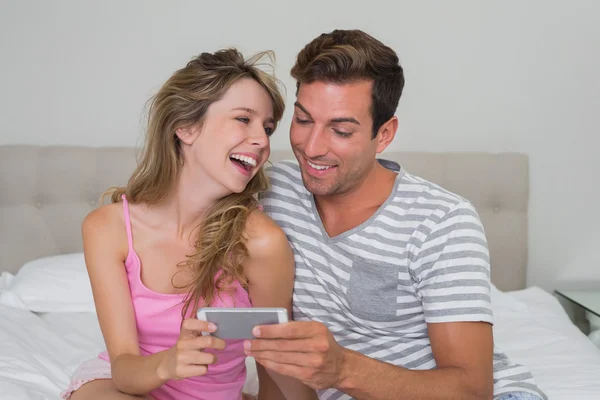 Casal alegre ler mensagem de texto na cama — Fotografia de Stock