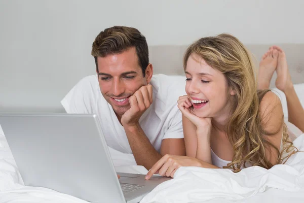 Happy young couple using laptop in bed Royalty Free Stock Photos