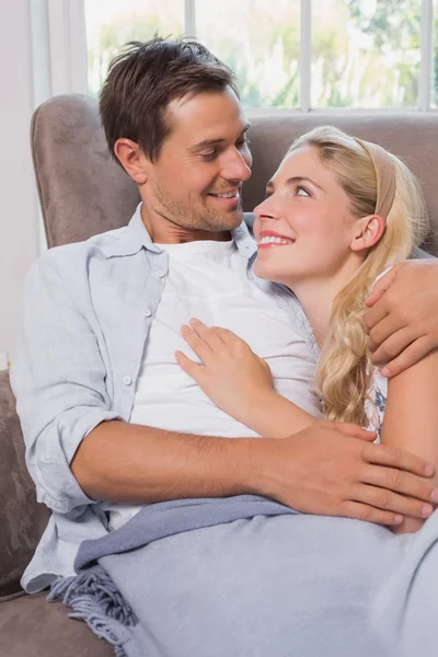 Loving couple looking at each other while lying on sofa Stock Photo