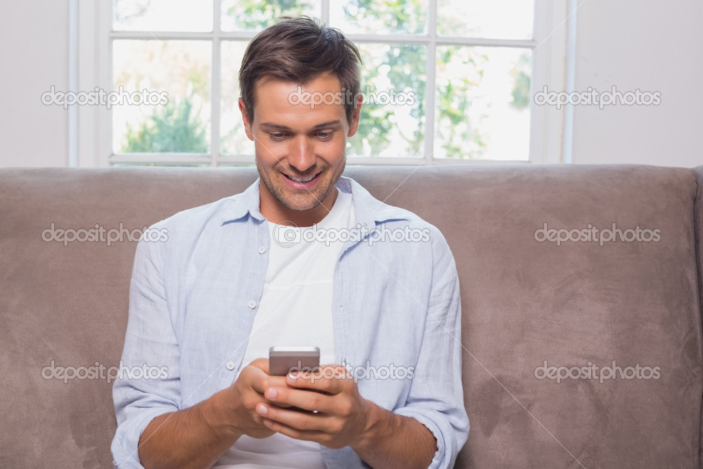 Casual man reading text message on sofa