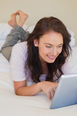 yatakta tablet bilgisayar kullanan kadın