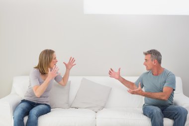 Unhappy couple having an argument in living room clipart