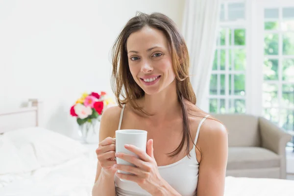 Mujer joven y relajada con taza de café en la cama — Foto de Stock