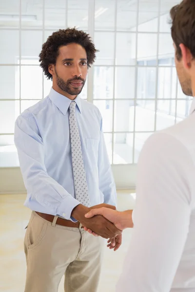 Serious businessmen shaking hands in office — Stock Photo, Image