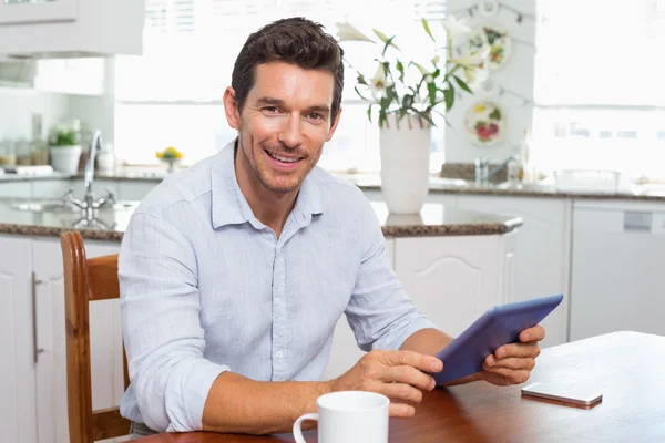 Homem sorridente usando tablet digital em casa — Fotografia de Stock