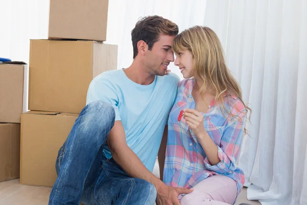 Couple holding new house key against cardboard boxes — Stock Photo, Image