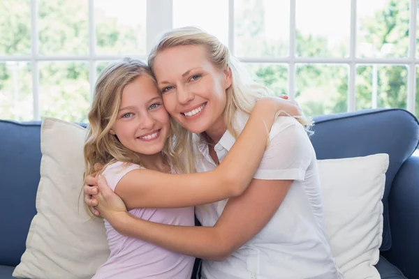 Счастливые мать и дочь обнимаются на диване — стоковое фото