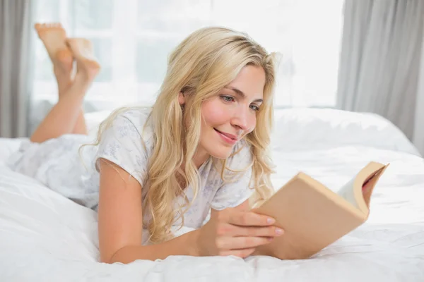 Beautiful casual young woman reading book in bed — Stock Photo, Image