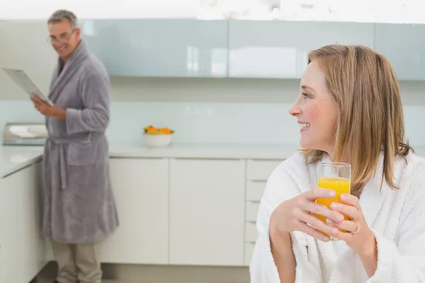 Mulher segurando suco de laranja com o homem no fundo — Fotografia de Stock