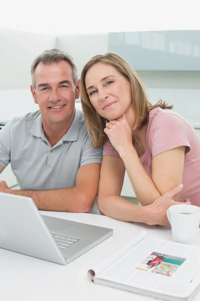 Retrato de um casal feliz usando laptop na cozinha — Fotografia de Stock