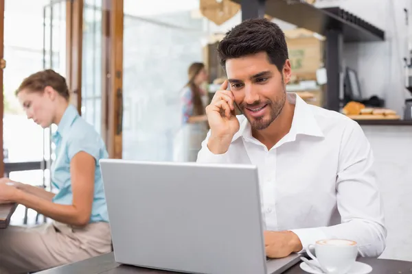 Man met laptop en mobiele telefoon in koffie winkel — Stockfoto