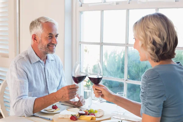 Šťastný starší pár opékání nápoje nad jídlem — Stock fotografie