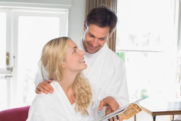 Casal olhando um para o outro enquanto lia revista em casa — Fotografia de Stock