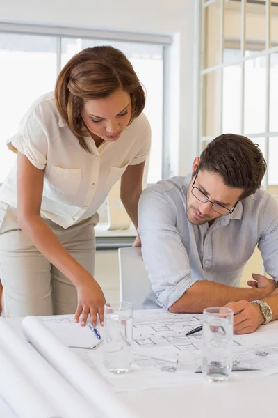 Concentrated colleagues working on blueprints at office — Stock Photo, Image