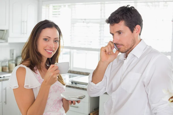 Vrouw drinken koffie terwijl man met mobiele telefoon thuis — Stockfoto