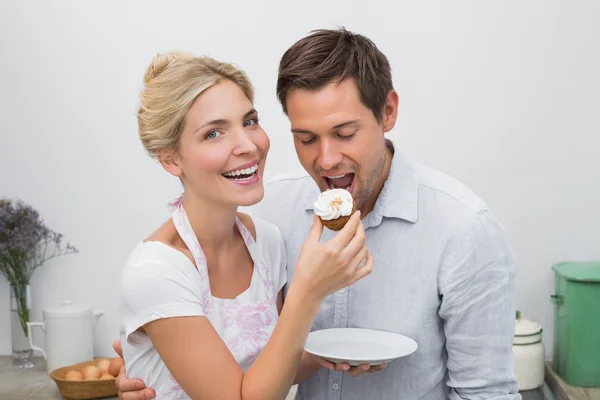 Happy young woman feeding man pastry at home — Stock Photo, Image