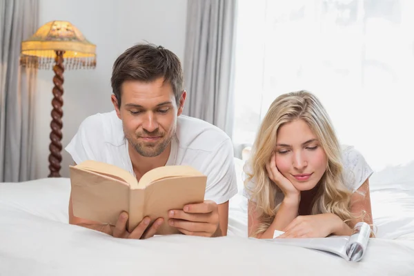 Расслабленная пара читает книги в постели — стоковое фото