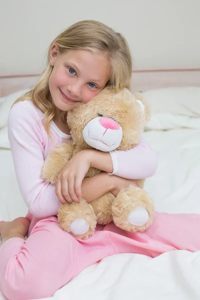 Young girl embracing stuffed toy in bed — Stock Photo, Image