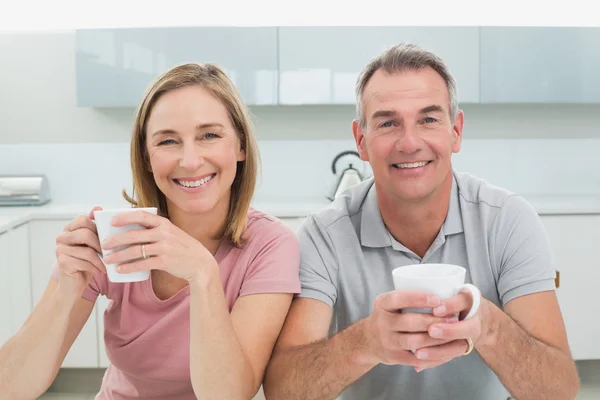 Happy relaxed couple with coffee cups in kitchen — Stock Photo, Image