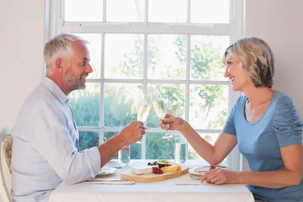 Side view of a mature couple toasting drinks over food — Stock Photo, Image