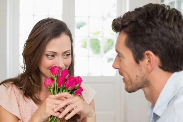 Woman looking at man with flowers at home — Stock Photo, Image