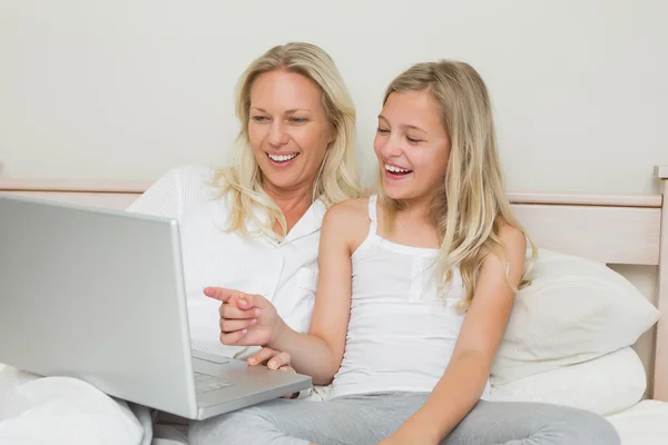 Mor och dotter med laptop tillsammans i sängen — Stockfoto