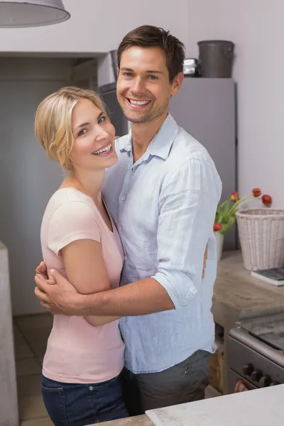 Feliz joven pareja abrazándose en la cocina — Foto de Stock