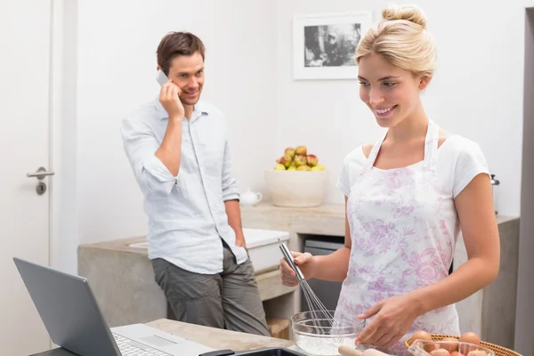 Woman preparing cookies while man on call in kitchen — Stock Photo, Image