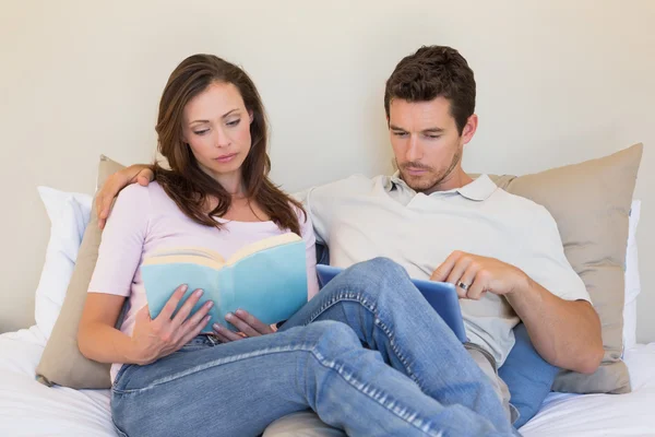 Couple concentré avec tablette numérique et livre à la maison — Photo