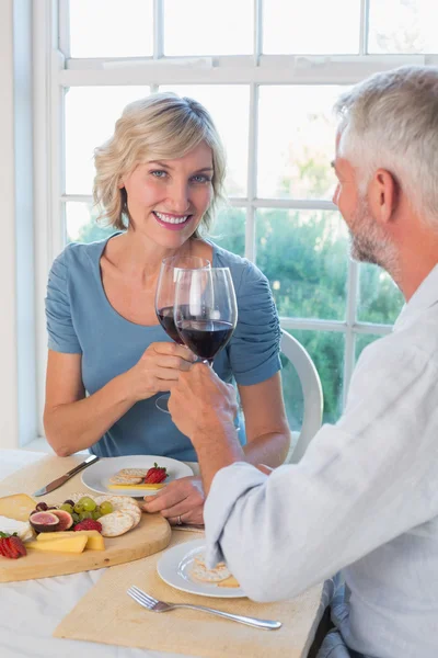 Reifes Paar stößt mit Weingläsern auf Essen an — Stockfoto