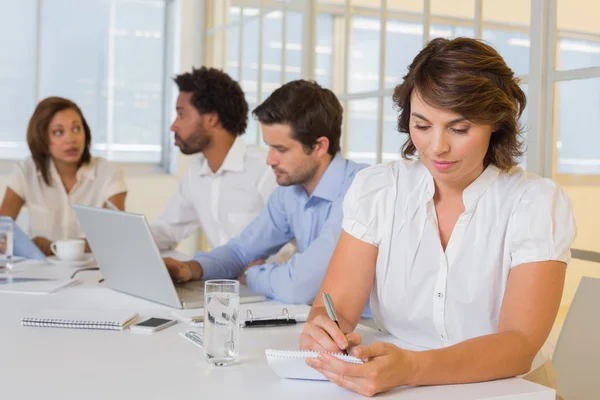 Empresária escrevendo notas com colegas em reunião no escritório — Fotografia de Stock