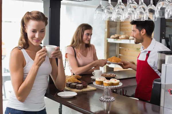 Frau trinkt Kaffee mit Freundin und Barista im Café — Stockfoto