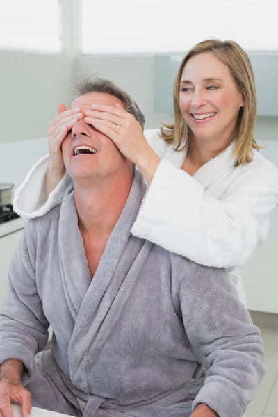 Donna sorridente che copre gli occhi dell'uomo in cucina — Foto Stock